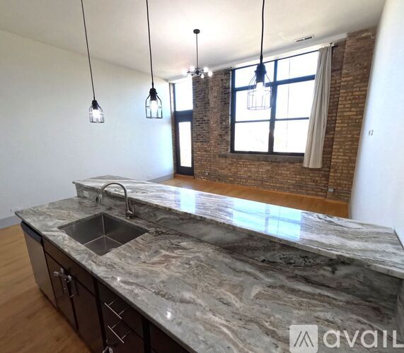 A kitchen with a marble countertop and pendant lights.