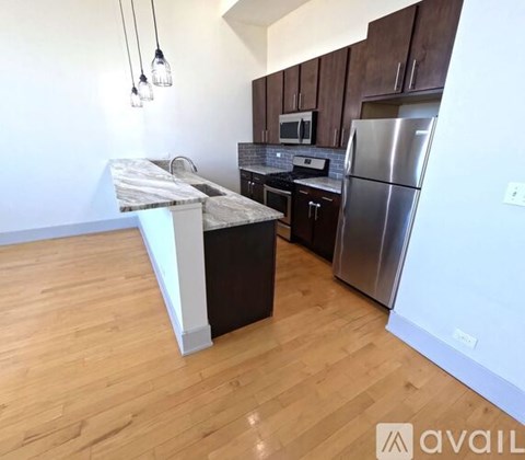 A kitchen with wooden cabinets and a marble island.