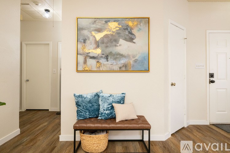 A painting hangs on a wall above a bench with blue cushions.