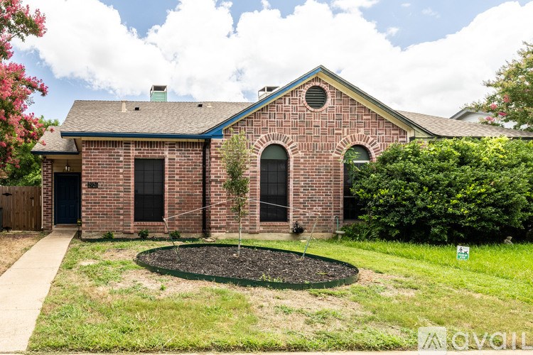 A red brick house with a black door and a small garden in front.