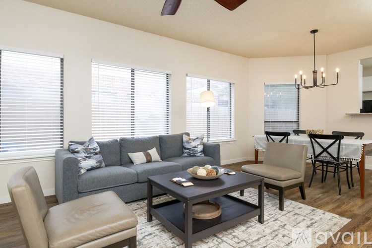 A living room with a grey couch, a brown chair, a coffee table, and a dining table with chairs.