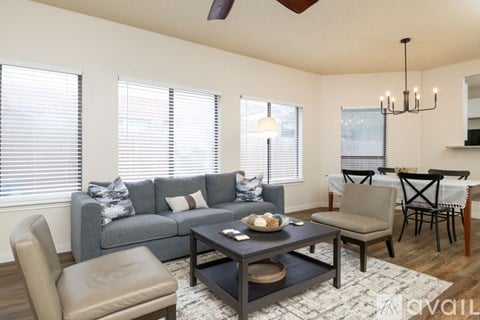 A living room with a grey couch, a brown chair, a coffee table, and a dining table with chairs.