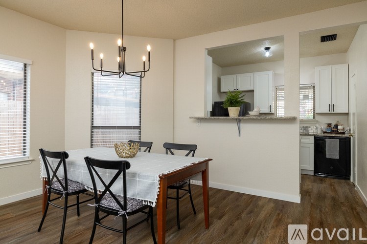 A dining room with a table set for four and a kitchen area in the background.
