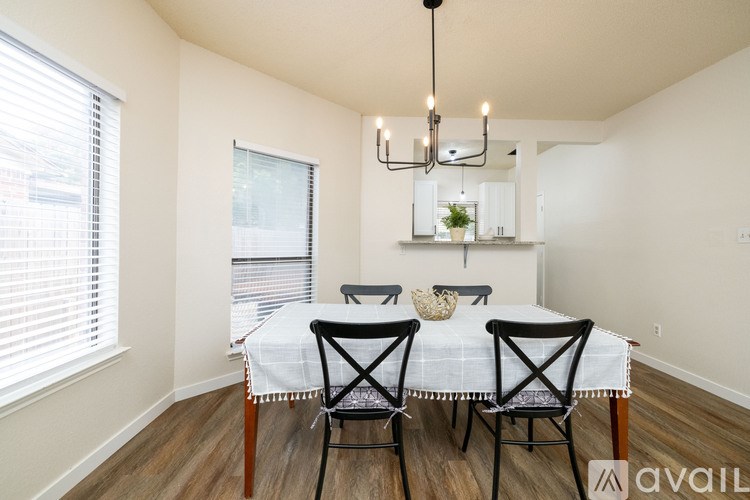 A dining room with a table set for two and a chandelier hanging from the ceiling.