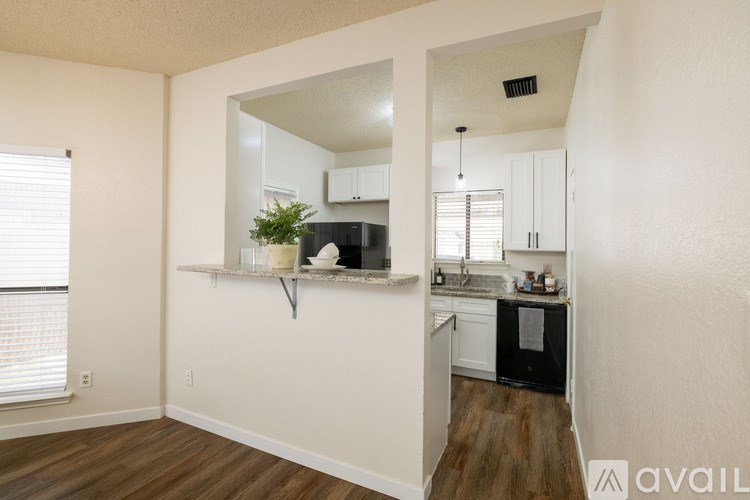 A kitchen with white cabinets and a black fridge is shown.