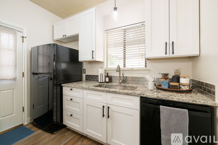 A kitchen with black appliances and white cabinets.