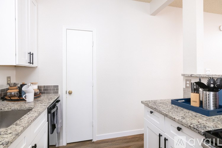 A kitchen with white cabinets and a granite countertop.