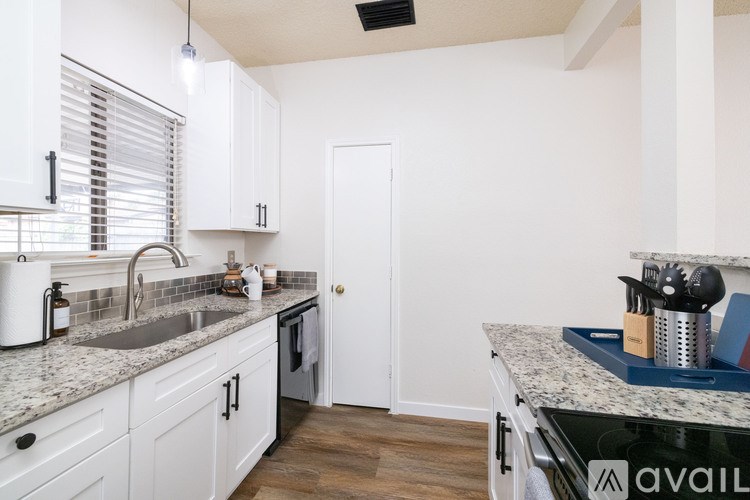 A kitchen with white cabinets and a marble countertop.