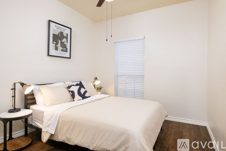A bedroom with a bed, a small table, and a picture on the wall.