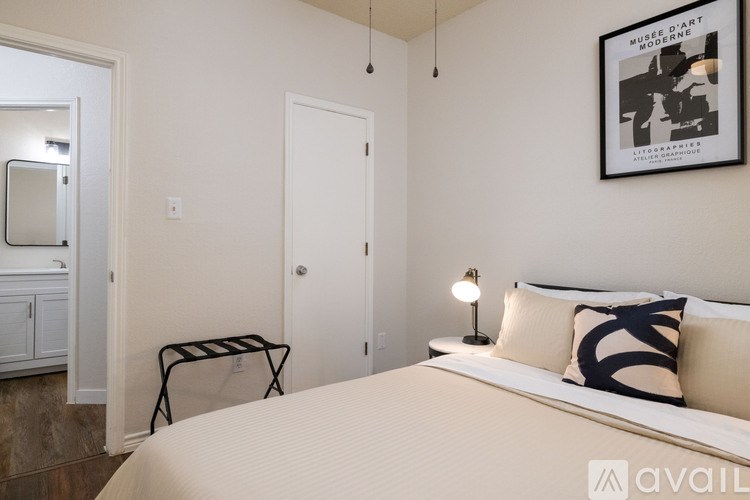 A bedroom with a bed, a nightstand, and a framed picture on the wall.