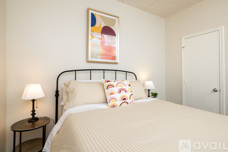 A bedroom with a bed, a lamp, and a painting on the wall.