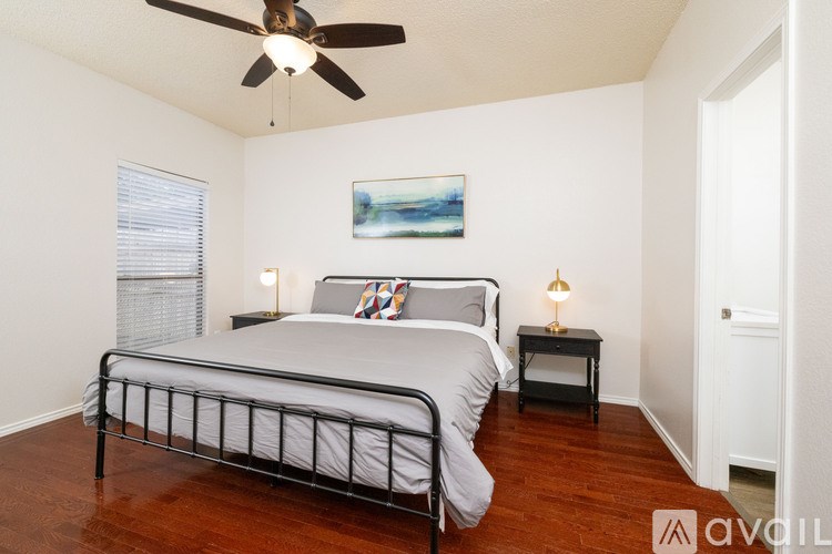 A bedroom with a bed, two lamps, and a painting on the wall.