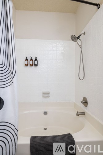 A bathroom with a white tub and a shower head.