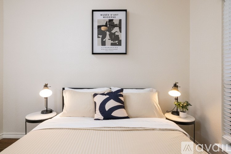 A bedroom with a bed, two lamps, and a framed picture on the wall.