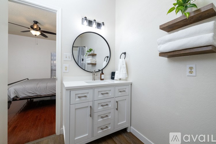 A bathroom with a white cabinet, a round mirror, and a plant on top of the cabinet.