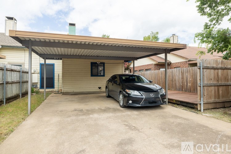 A black car is parked in a driveway under a covered garage.