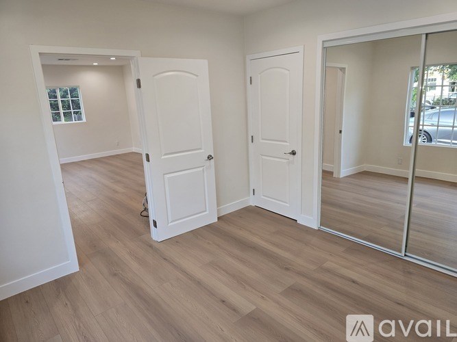 A room with white doors and wooden flooring.