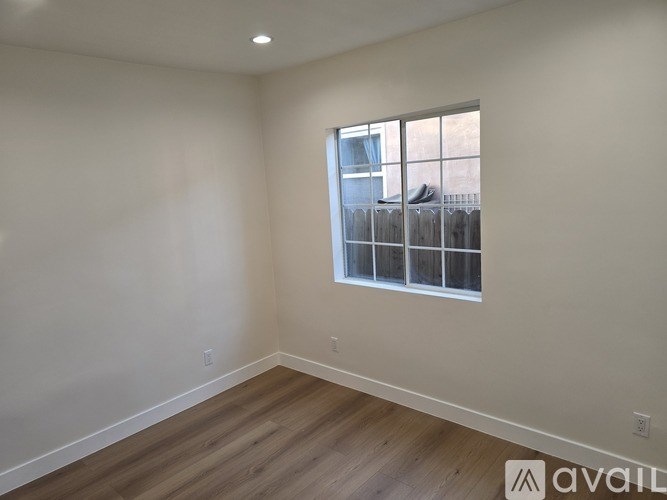 A room with a window and wooden flooring is available for rent.