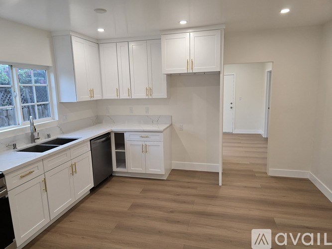 A kitchen with white cabinets and a wooden floor.