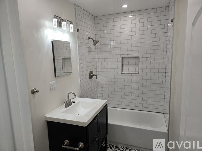 A bathroom with a white sink and black cabinet.