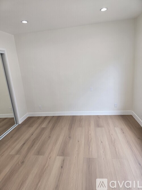 A room with wooden flooring and a white wall.