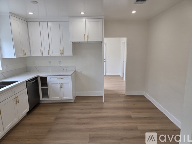 A kitchen with white cabinets and a wooden floor.