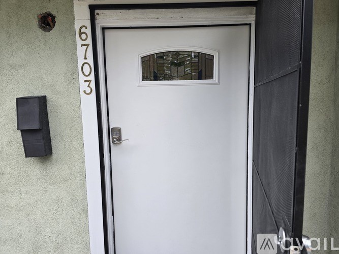 A white door with a black handle and a black mailbox on a light green wall.