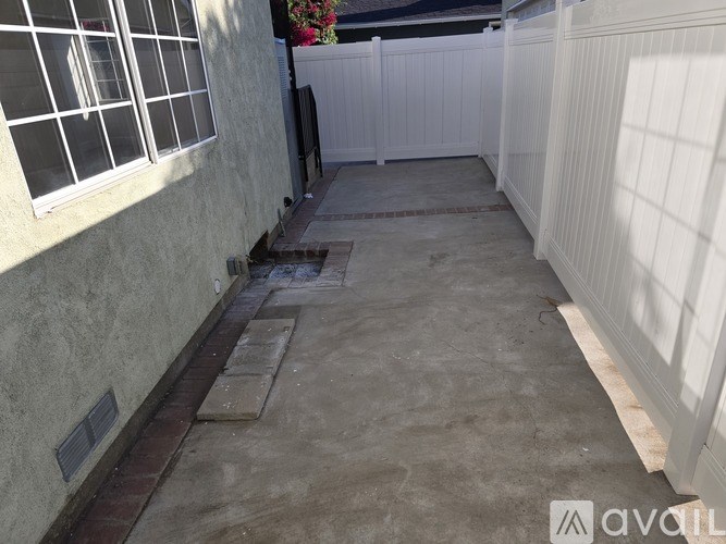 A patio area with a white fence and a grey wall.