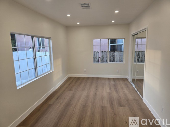 A room with wooden flooring and two windows.