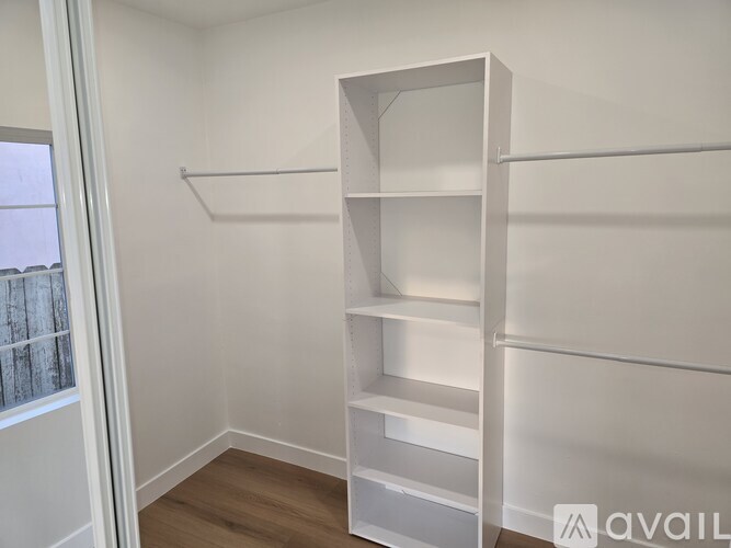 A white shelving unit in a room with a window.