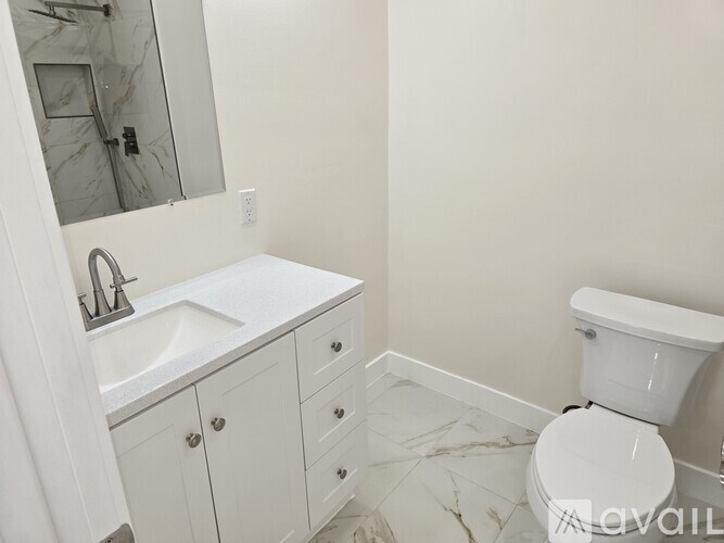 A white bathroom with a toilet, sink, and mirror.