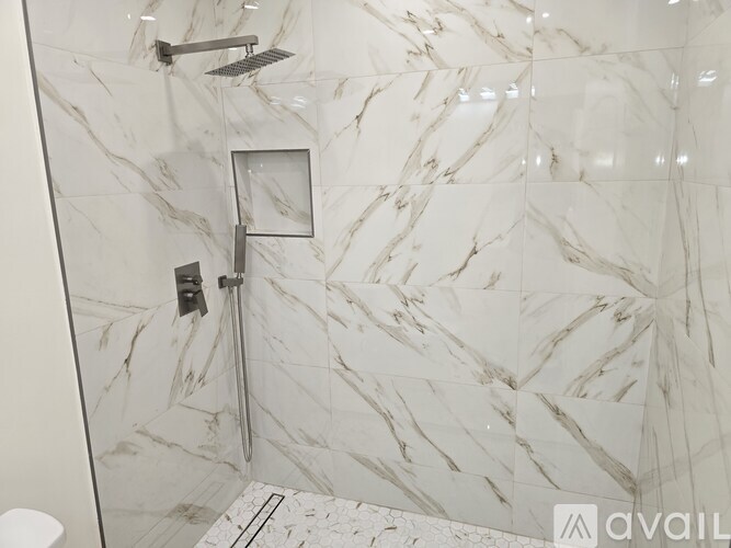 A bathroom with marble tiles and a shower.
