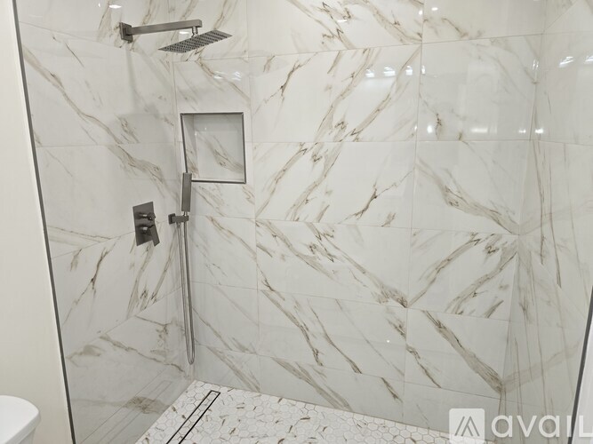 A bathroom with a marble tile shower and a glass door.