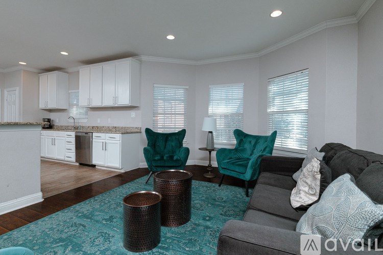 A living room with a grey couch and two green chairs.