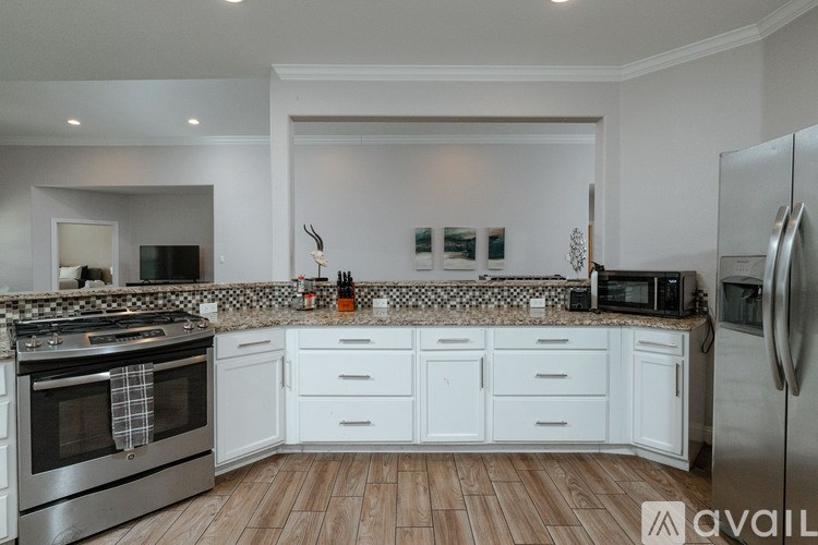 A kitchen with white cabinets and a wooden floor.