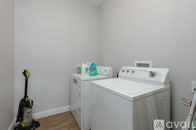 A white washing machine and a green vacuum cleaner in a small room.