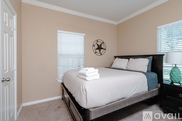 A bedroom with a bed, nightstand, and window with blinds.