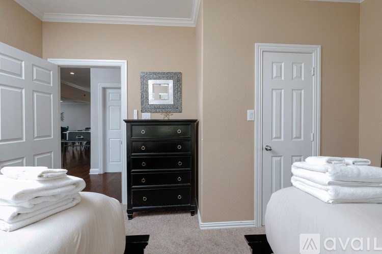 A room with a white bed, a black dresser, and a white door.