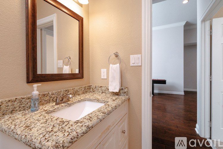 A bathroom with a granite countertop and a mirror above the sink.
