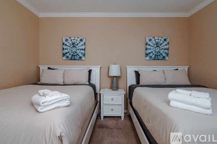 Two twin beds with white towels on top and a white nightstand between them.