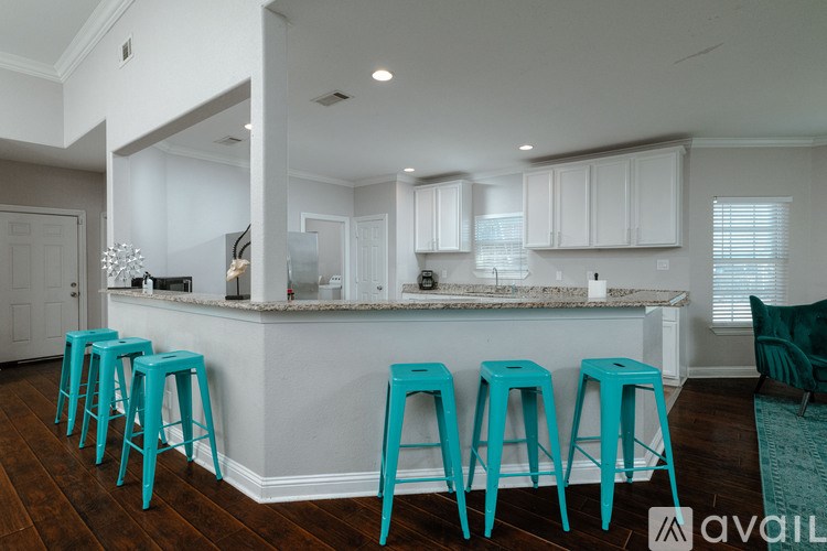 A kitchen with a bar area and blue stools.