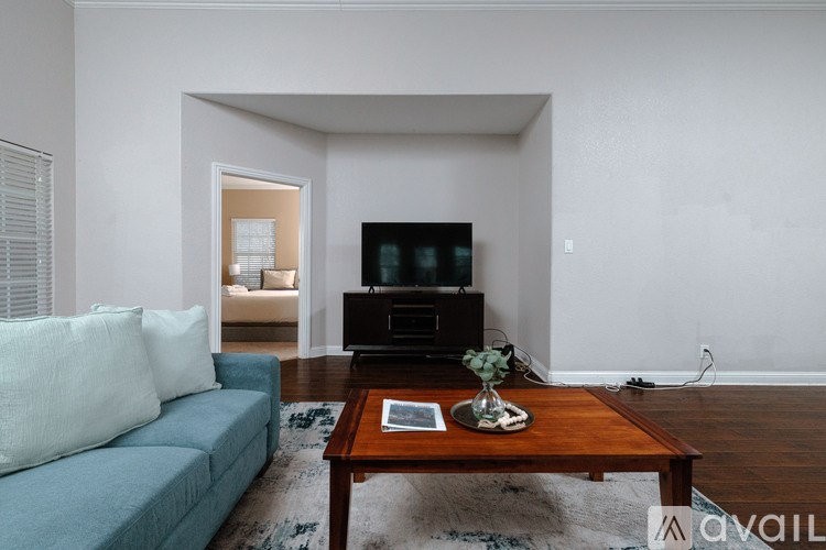 A living room with a blue couch, a wooden coffee table, and a television.