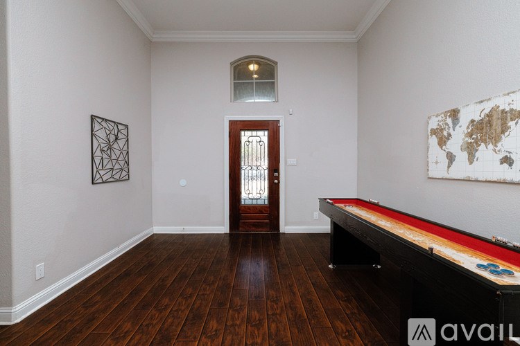 A pool table is in a room with wood floors and a door.