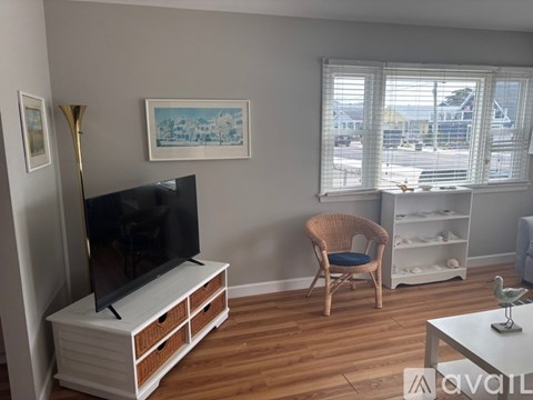 A living room with a television, chair, and a painting on the wall.
