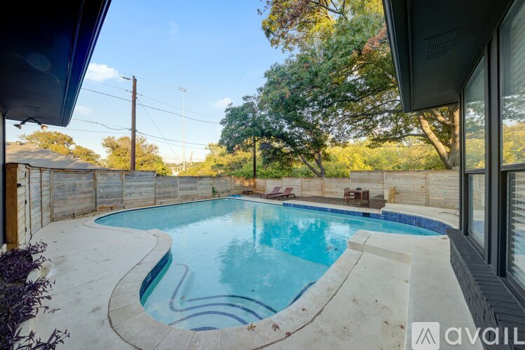 A small in-ground pool with a concrete patio and a wooden fence.