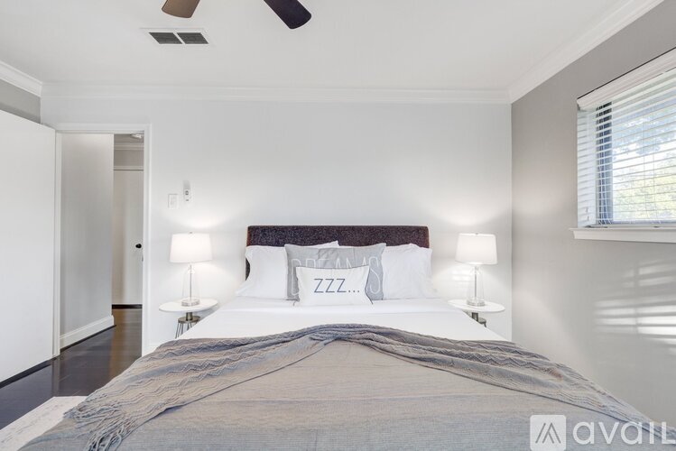 A bedroom with a large bed and two lamps.