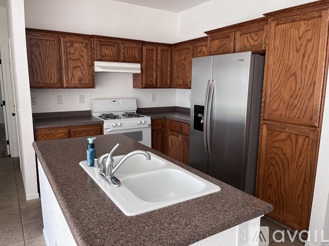 A kitchen with a stove, sink, and refrigerator.