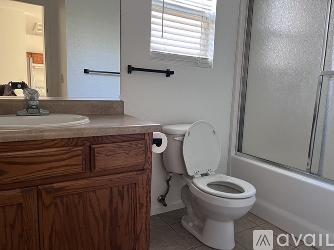 A white toilet with the seat up is in a bathroom with a wooden vanity.
