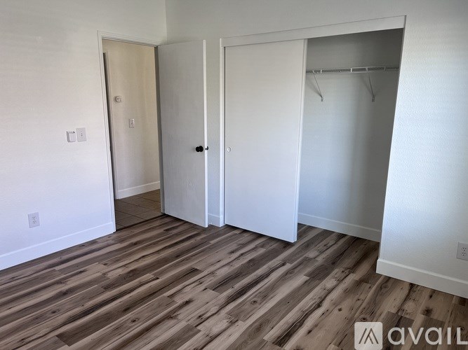 A room with a wooden floor and three doors.