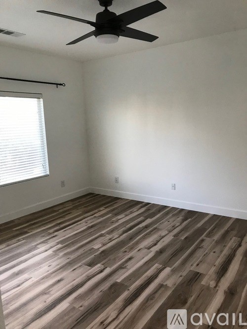 A room with a ceiling fan and wooden flooring.